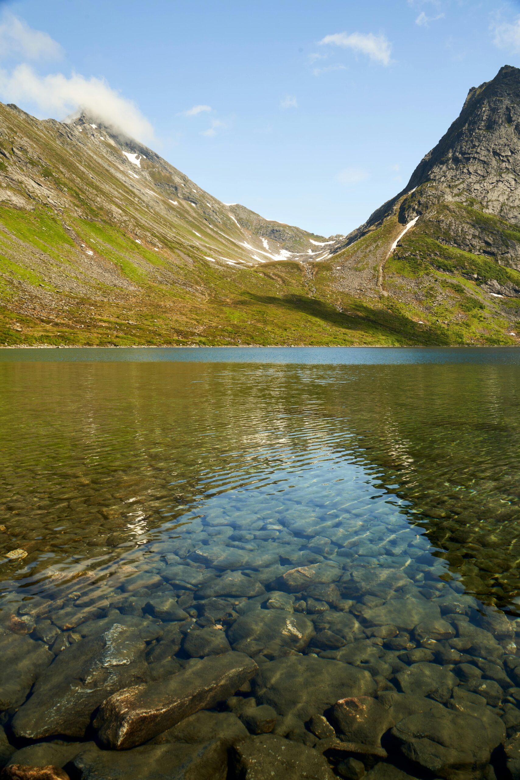Serene mountain landscape with a clear lake reflecting the blue sky and rugged peaks.