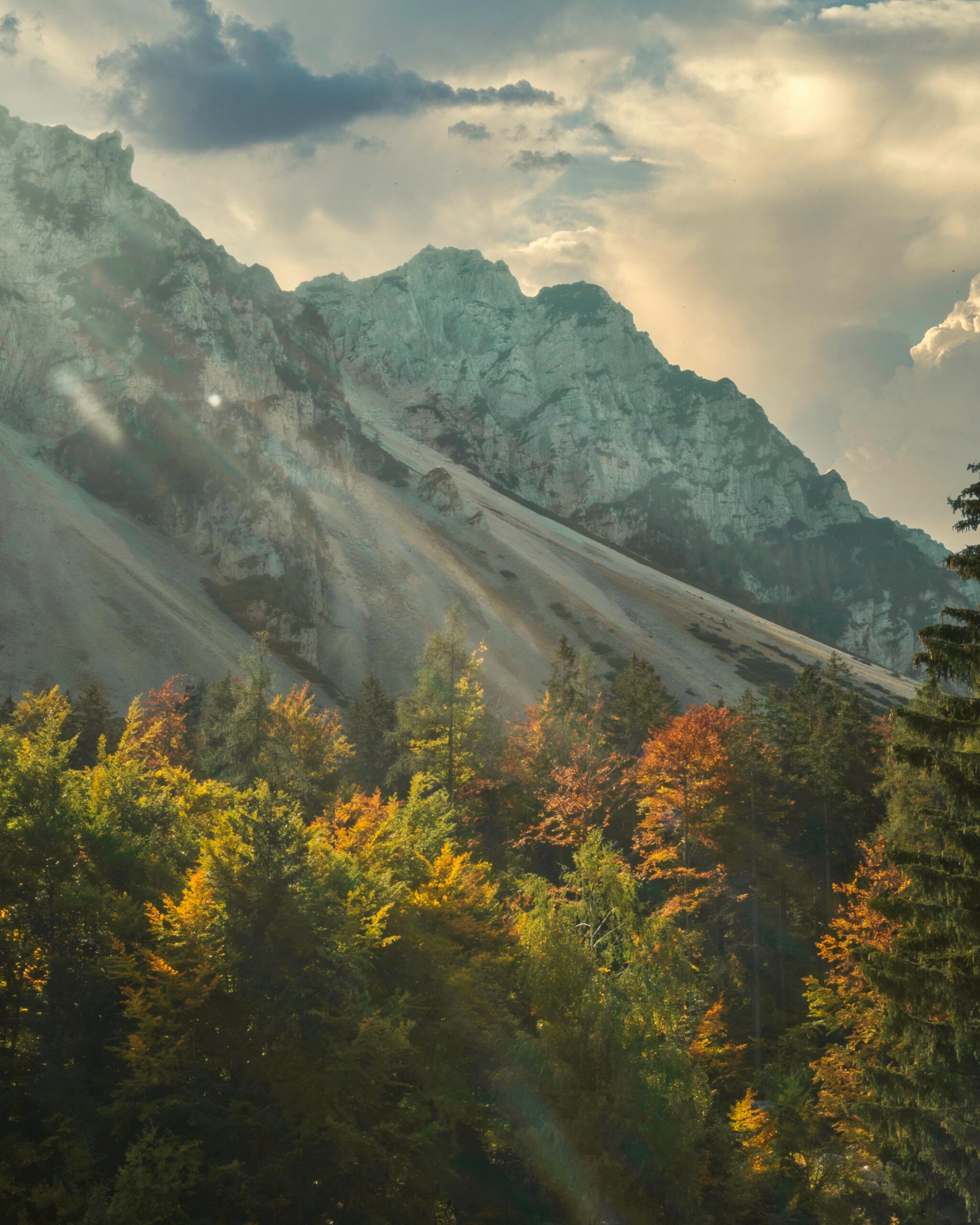 Vibrant autumn mountain landscape in Klagenfurt, Austria with sun rays through clouds.